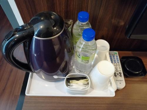 a tea kettle on a tray with bottles of water at T+ Hotel Sungai Korok in Alor Setar