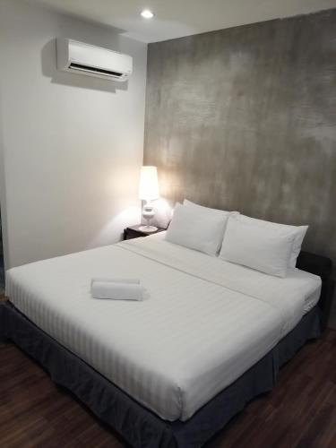 a bedroom with a white bed and a lamp at T+ Hotel Sungai Korok in Alor Setar