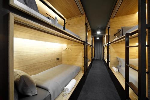 two bunk beds in a room with wooden walls at The Pod at Beach Road Boutique Capsule Hotel in Singapore