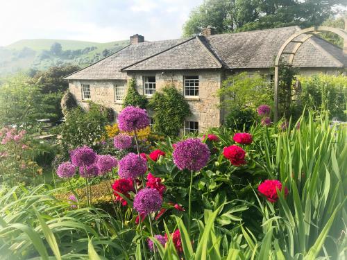 a garden with flowers in front of a stone house at Pen-Y-Dyffryn Country Hotel in Oswestry