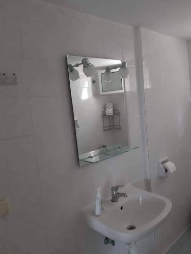 a white bathroom with a sink and a mirror at Ianos in Nea Skioni
