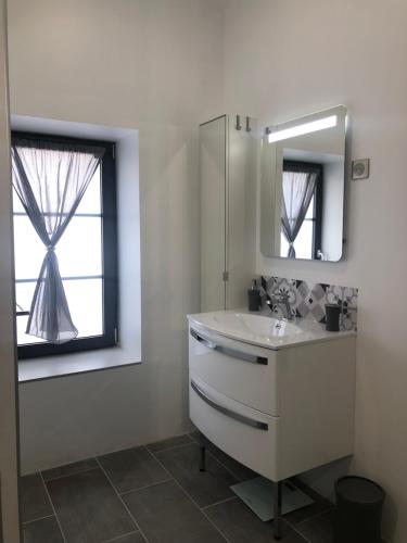 La salle de bains blanche est pourvue d'un lavabo et d'un miroir. dans l'établissement La Grange, à Ury