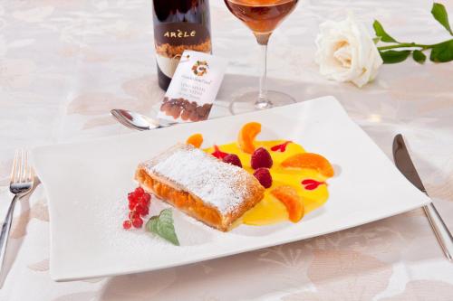 ein weißer Teller mit einem Stück Kuchen und Obst in der Unterkunft Viridis Hotel in Revò