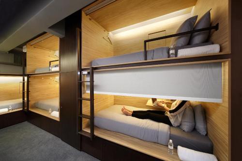 a room with bunk beds with a woman laying on the bed at The Pod at Beach Road Boutique Capsule Hotel in Singapore