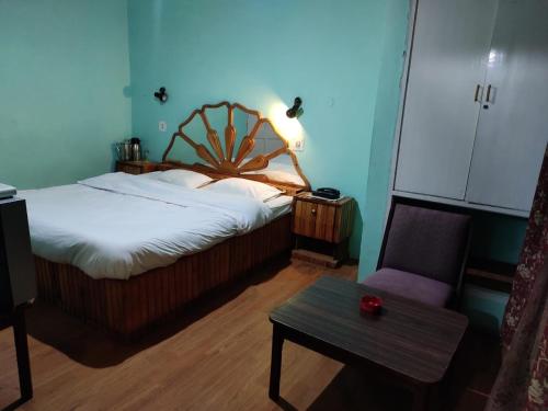 a bedroom with a bed and a table and a chair at Hotel Madhuban Shimla in Shimla
