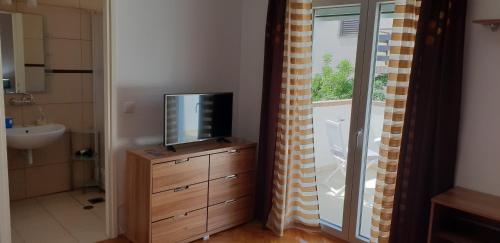 ein Badezimmer mit einem TV auf einer Kommode neben einem Fenster in der Unterkunft Apartments Perina in Tisno