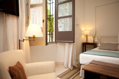 a bedroom with a bed and a chair and a window at Balcón de Córdoba in Córdoba
