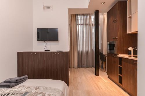 a bedroom with a bed and a tv and a kitchen at CACAO Studio next to Crystal Garden and Russian Church in Sofia