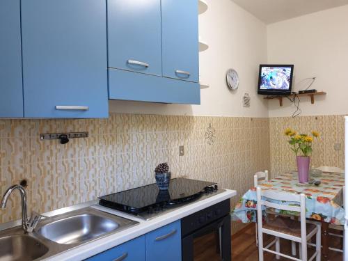 cocina con armarios azules, fregadero y mesa en Casa Vacanze Fontanelle en Badolato