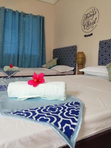 two beds in a room with blue curtains and a red flower on them at Happy's Homestay in Boracay