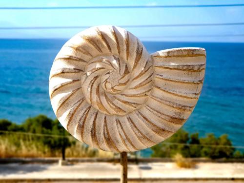 a shell sculpture in front of the ocean at Derveni Seaside Apartments - Deluxe Sea View Penthouse Jacuzzi-BBQ & Groundfloor Garden View Apartment in Derveni
