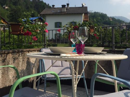 a table with two wine glasses on a balcony at CA' del GIACOMINO in Baselga di Pinè