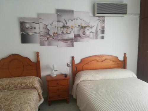 a bedroom with two beds and a tv on the wall at Pension La Linea in Puerto de Mazarrón