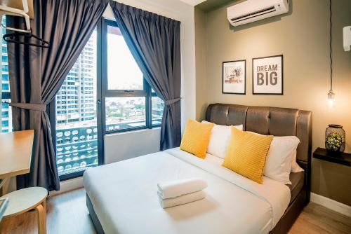 um quarto com uma cama com almofadas amarelas e uma grande janela em Arte Plus by Cobnb KLCC em Kuala Lumpur