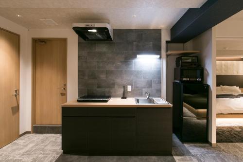 eine Küche mit einem Waschbecken und ein Bett in einem Zimmer in der Unterkunft Hotel Kado Gosho-Minami Kyoto in Kyoto