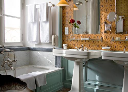a bathroom with a sink and a tub and a mirror at La Mirande in Avignon