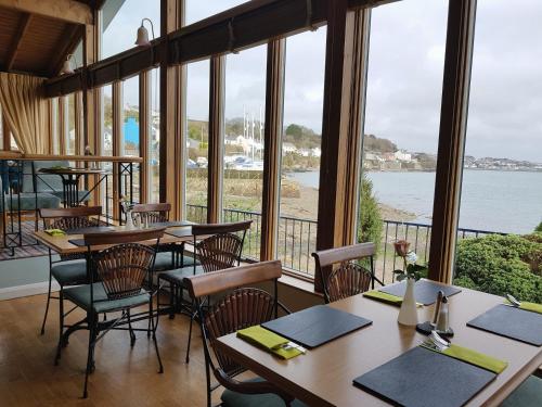 restauracja ze stołami i krzesłami oraz widokiem na wodę w obiekcie Ferry House Inn w mieście Milford Haven