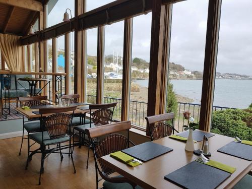 a restaurant with tables and chairs and a view of the water at Ferry House Inn in Milford Haven