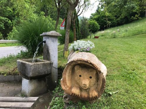 a bird bath with a bear head in the grass at Apartma & savna Slapnik in Luče