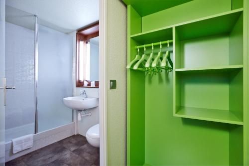 a bathroom with green walls and a toilet and a sink at Campanile Le Havre Nord - Montivilliers in Montivilliers