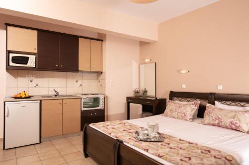 a bedroom with a large bed and a kitchen at Dryades Apartments & Studios in Skala Potamias