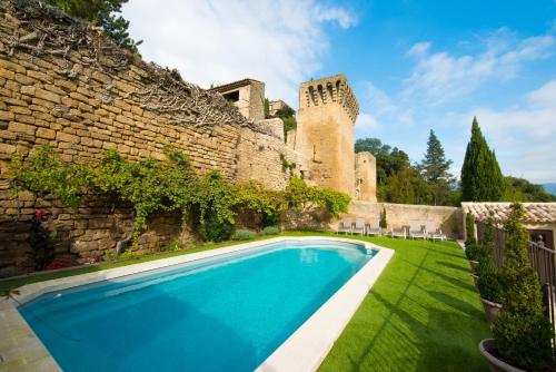 a swimming pool in front of a building with a castle at La Treille et L'Impasse in Ansouis