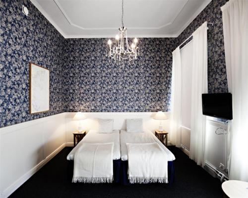 a bedroom with a bed and a chandelier at First Hotel Statt in Söderhamn