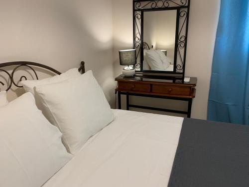 a bedroom with a white bed and a mirror at Christi Apartments Α&Β in Kokkíni Khánion