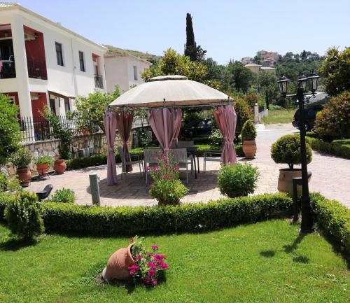 a patio with an umbrella and flowers in a yard at Delphin Rooms Sivota in Sivota