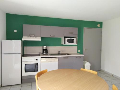 a kitchen with a table and a white refrigerator at Pescalis Résidence Les Maisons du Lac in Moncoutant