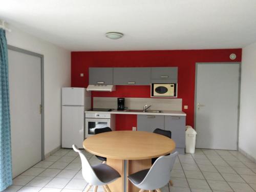 a small kitchen with a wooden table and chairs at Pescalis Résidence Les Maisons du Lac in Moncoutant