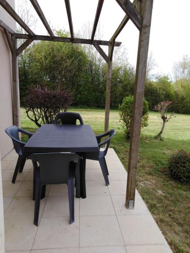 a black table and chairs sitting under a pergola at Pescalis Résidence Les Maisons du Lac in Moncoutant