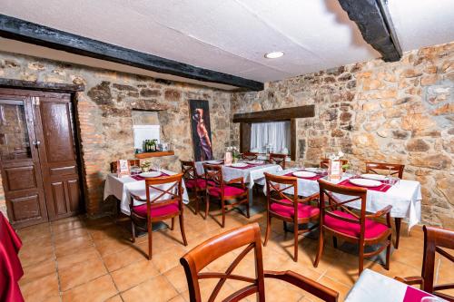 a restaurant with tables and chairs and a stone wall at Albergue Santa Marina in Buelna