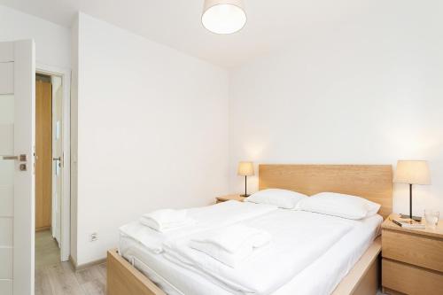 a white bedroom with a large bed with white sheets at Apartments Claro II by Renters in Krakow