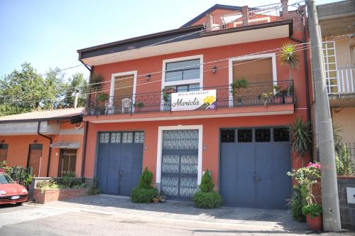 um edifício laranja com portas azuis e uma varanda em Mariclà em Viagrande