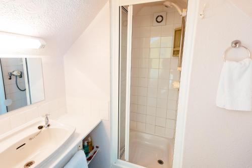 bagno bianco con lavandino e doccia di Surfside Stop a Newquay