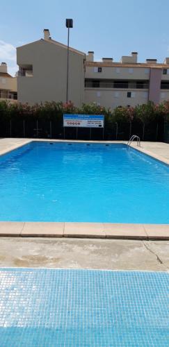 une grande piscine bleue devant un immeuble dans l'établissement Résidence les Floralies 2 - Avenue de Camargue, au Grau-du-Roi