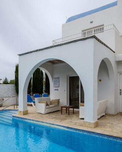 a pool with an archway next to a villa at Thalassines Villas in Ayia Napa