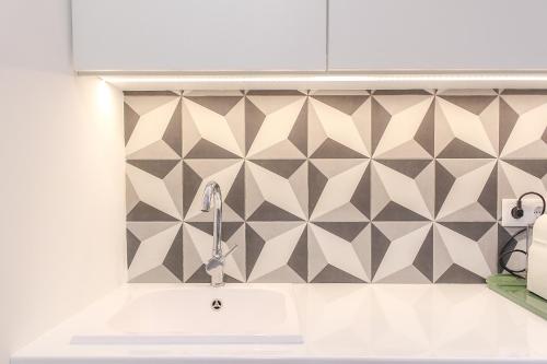 a kitchen with a sink and a geometric tile wall at PORTO CONCEPT HOME - Paranhos in Porto