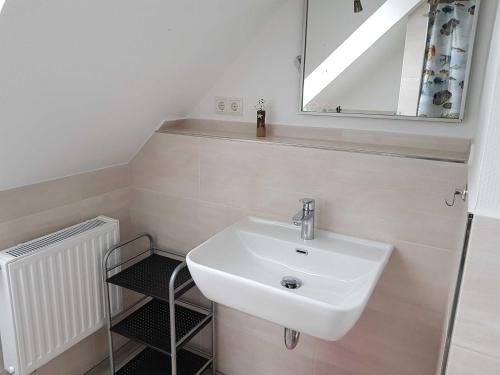 La salle de bains est pourvue d'un lavabo blanc et d'un miroir. dans l'établissement Ferienwohnung Klütz, à Oeversee