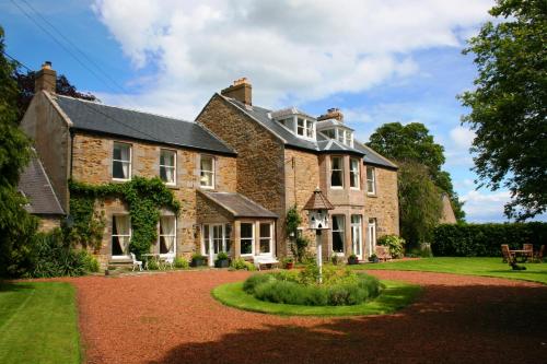 a large brick house with a garden in front of it at The Old Parsonage Country House in Berwick-Upon-Tweed