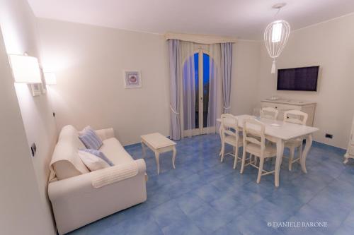 Baia Delphis Resort في فاستو: غرفة معيشة مع أريكة بيضاء وطاولة