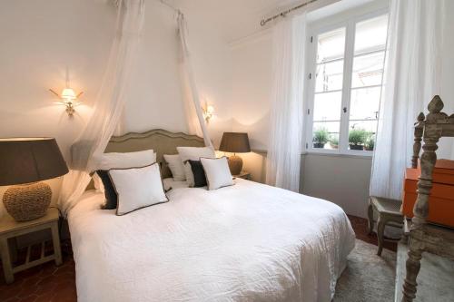 une chambre avec un lit avec des draps blancs et des oreillers dans l'établissement Le Pigeonnier, à Saint-Tropez