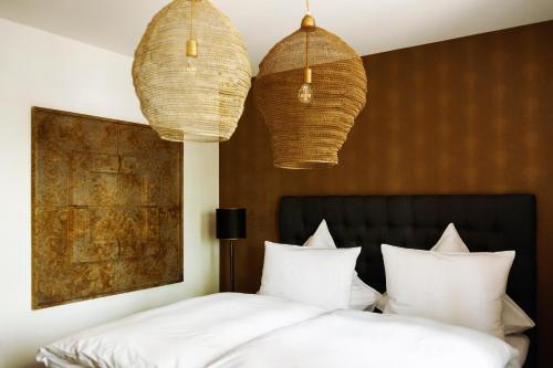 a bedroom with two white beds and two hanging lights at Boutique Hotel Kauers in Verl