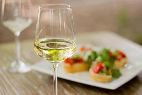 a glass of white wine next to a plate of food at Boutique Hotel Kauers in Verl