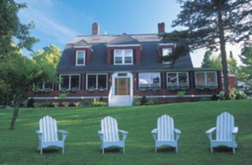 three chairs sitting in the grass in front of a house at Inn at Jackson in Jackson