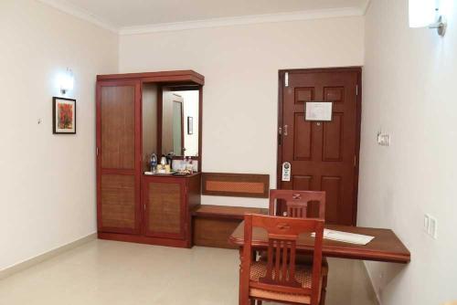 Habitación con escritorio de madera y espejo. en Kallada hotels, en Trichūr