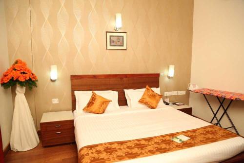 1 dormitorio con 1 cama y un jarrón de flores en Kallada hotels, en Trichūr