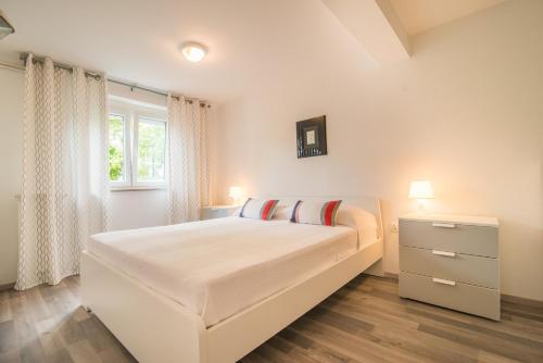 a white bedroom with a large bed and a window at Apartment Complex Kampic in Poreč