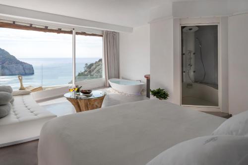 a bedroom with a bed and a bath tub and a window at Hacienda Na Xamena, Ibiza in Na Xamena